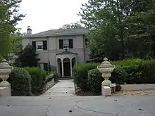 Photo of a two-story brick home painted grey with black shutters.