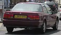  Rear view of a two-door car with a three-box body style.