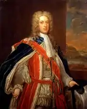 A three-quarter portrait of a man wearing 18th-century dress. He wears a white frock, under a red coat, topped by a blue gown.  He wears a large gold chain around his neck, which descends as far as his chest. He has a long white wig, and behind him a portrait of a shoreline is visible.