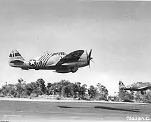 a pair of Republic P-47 Thunderbolt fighter planes flying low over an airfield