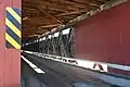 A picture showing the inside of the covered bridge from an angle to show decking and road bed