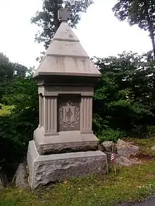 A granite monument with a pyramidal peak, capped by a Maltese cross, etched with an inscription, "22nd Mass Infantry".