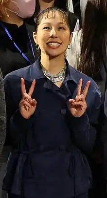 Portrait of Ai wearing a navy blue outfit while posing a V sign formed with both of her hands