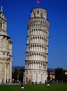 The flag of Pisa (Pisan cross) flying on the Leaning Tower of Pisa (built 12th–14th century)