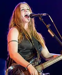 A woman in a black jacket smiling in front of a microphone on a stage.