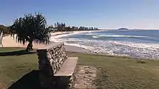 The view of people surfing at Alexandra Headland Beach with Mount Coolum in the background.