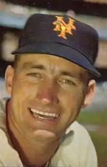 A man in a white baseball jersey and black cap