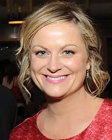 A shot of a blond woman wearing a red dress, smiling into the camera.