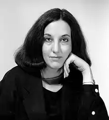 black and white photo of a woman with shoulder-length hair, her left hand raised to her cheek