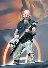 Bald, bearded, tattooed man playing guitar onstage