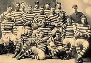 Photo of team players and management all of whom are seated or standing, wearing either their playing jerseys with caps, or formal wear.