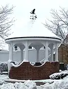 A gazebo during winter, topped with a weather vane