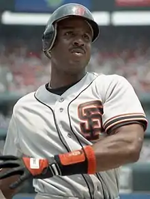 Baseball player wearing a San Francisco Giants uniform and a black betting helmet, while swinging a baseball bat