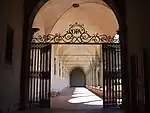 A gate in the gardens with the letters "OPA" for ora pro animis ("pray for souls")