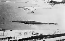 Black and white aerial photograph showing an overturned ship