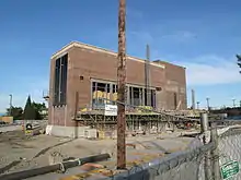 An unfinished building surrounded by a fenced-off dirt lot