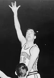 A basketball player, wearing a jersey with a word "PRINCETON" and the number "42", is jumping in front of another basketball player who is wearing a jersey with the number "24".