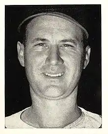 A close-up of a smiling man wearing a baseball jersey and cap