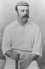 Billy Murdoch sitting holding a bat