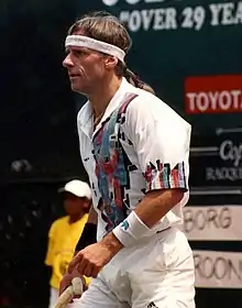 A brown-haired man in a white polo shirt