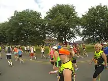 Many people running a marathon on a street. There are trees in the background.