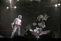 Roger Daltrey holding a microphone and Pete Townshend jumping on stage