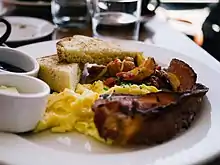 Scrambled eggs, bacon, and toast on a plate in a restaurant.