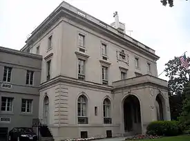 A three-story gray mansion, with a covered front entrance