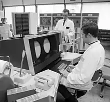 Operator console of the CDC 6400 with four magnetic tape memory units in the background with a magnetic tape controller unit in front of them at the Rechenzentrum (Computer Center) of RWTH Aachen University, Germany (1970).