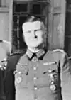 A man wearing a military uniform with an Iron Cross displayed at the front of his uniform collar.