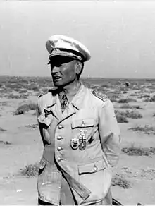 Upper body of a man wearing a military uniform with an Iron Cross displayed at the front of his uniform collar.