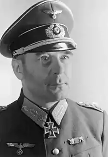 A man wearing a military uniform and peaked cap with an Iron Cross displayed at the front of his uniform collar.