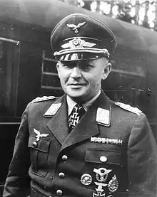 Black-and-white picture of a man with peaked cap, military uniform displaying various military decorations.