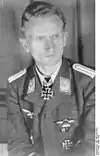 A man wearing a military uniform with an Iron Cross displayed at his neck.