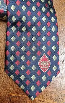 a necktie with a red on blue pattern and a badge showing the date of founding: 1214