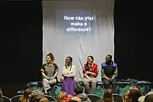 Four actors stand below a projection that reads "How can you make a difference?"