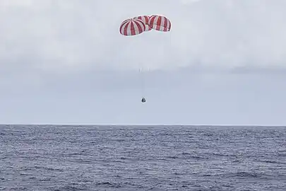 Dragon descending under parachutes