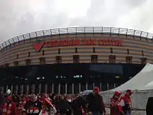 People milling about a large brick color building with large sign Canadian Tire Centre