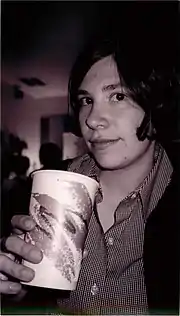 A young woman with short dark hair, holding a paper cup