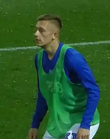 Lean young man with short fair hair wearing sports kit