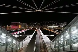 Gravel-topped platform canopies with red trains on the tracks between them