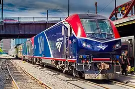 A blue diesel locomotive with a curved white stripe, red nose, and a red sill stripe