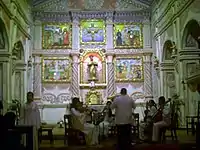 A string concert performed by people in white robes sitting in front of the altar.