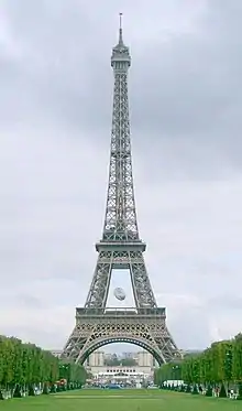 An avenue of trees leads to a large iron lattice tower, in which an oversized rugby ball hangs within the lower sections.