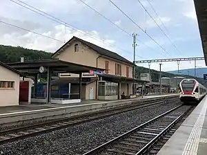 Red-white-and-blue train passes two-story building