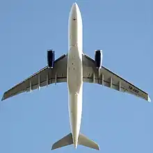 The undercarriage of an A330 have been retracted, showing an underside view of an A330 during flight. Under each wing is a turbofan engine.