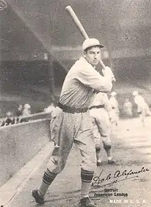 A man wearing a baseball cap and jersey poses prior to swinging his baseball bat.