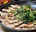 Dallae-muchim (seasoned wild chives) on samgyeopsal (grilled pork belly)