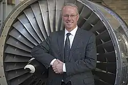 Dr. Dave Miller, NASA Chief Technologist, posing in front of an airplane engine