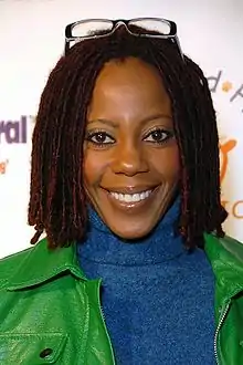 A 57-year-old woman with curly brown hair, looking at something to the left of the camera.